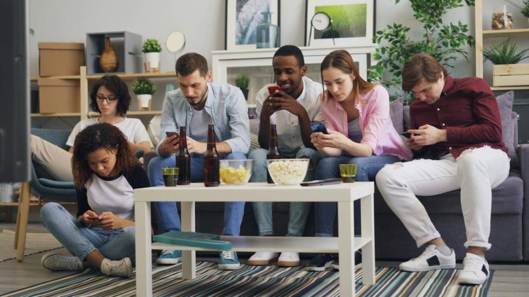 a group of people sitting on a couch and using their cell phones