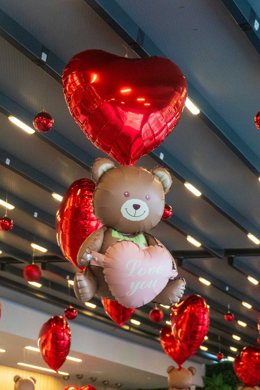 colorful heart balloons with teddy bear in cafe